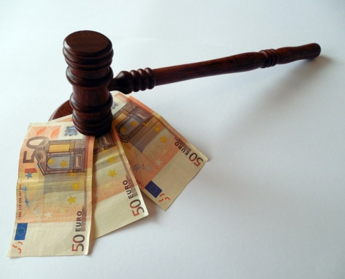 Foto de un mazo de juez con tres billetes de 50 euros debajo, imagen que ilustra el artículo de Ponter Abogados y Asesores sobre "Proporcionalidad en la sanción por no consignar cuotas en la autoliquidación del IVA"